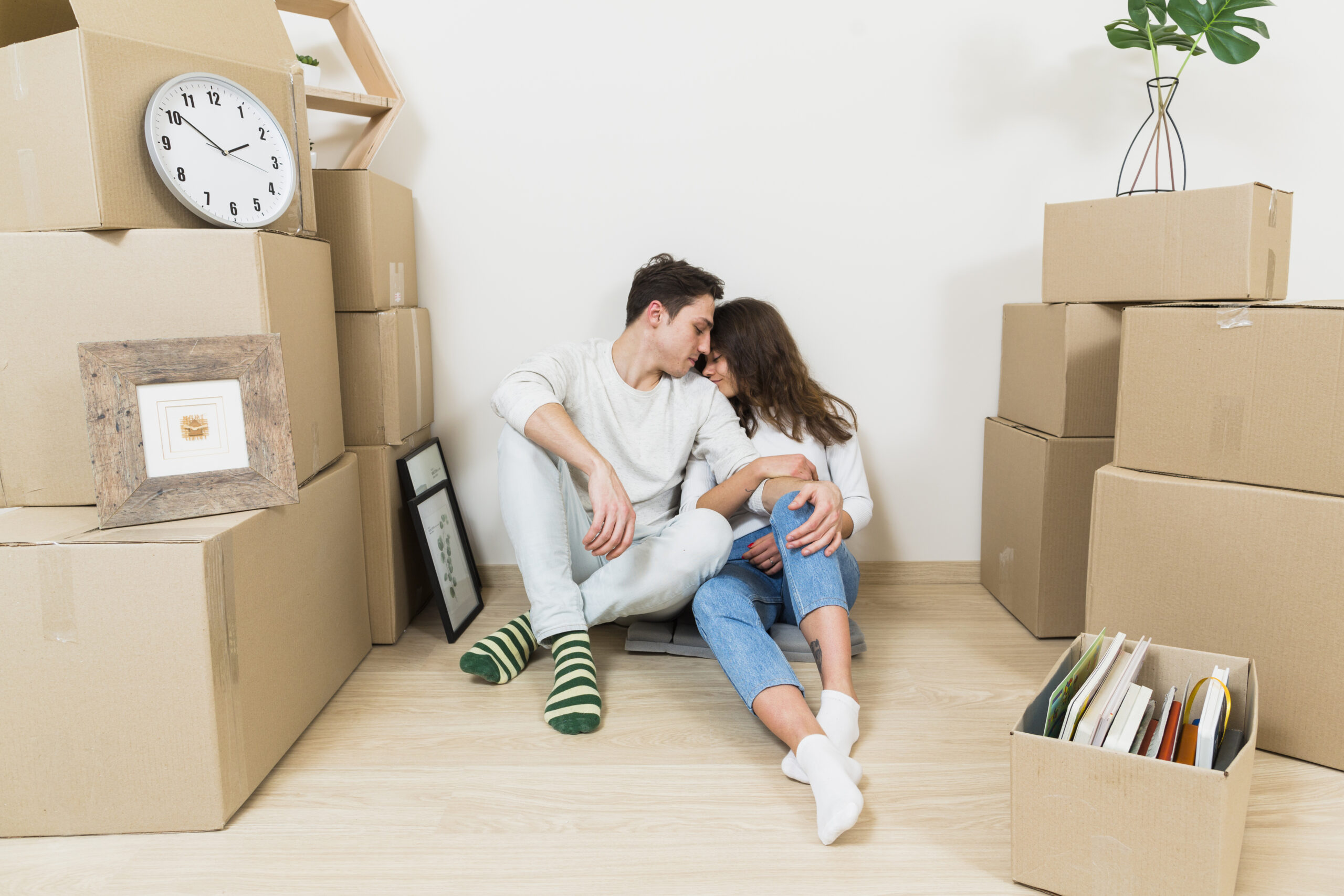 loving-young-couple-sitting-stack-cardboard-boxes-their-new-apartment